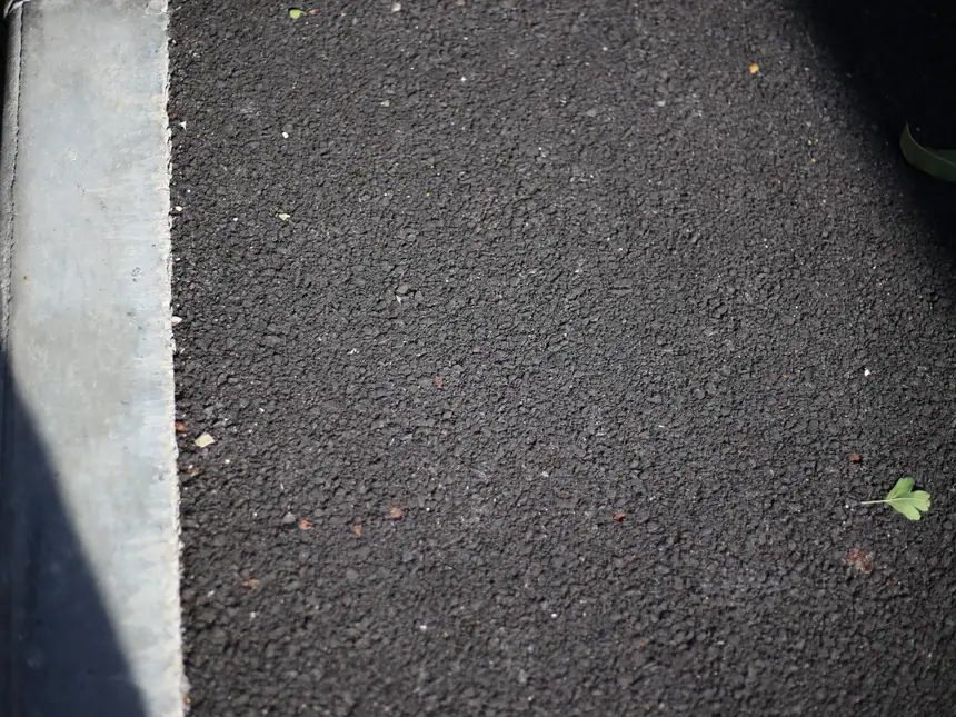 The edge of a newly surfaced path in shadow