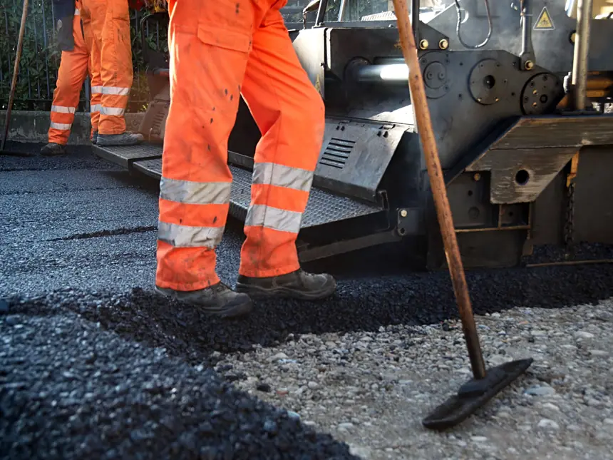 A road crew raking out hot asphalt