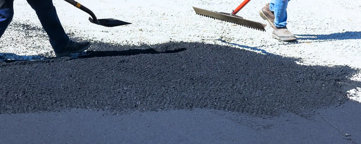 An operative raking the edge of a fresh surface — Road Resurfacing in Folkestone by Meads Resurfacing