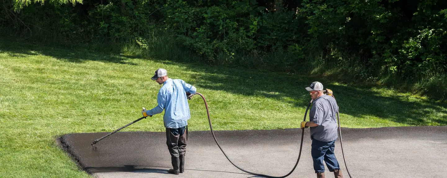 Bitumen sealant being squeegeed across a surface — Surface Dressing in Greenwich by Meads Resurfacing