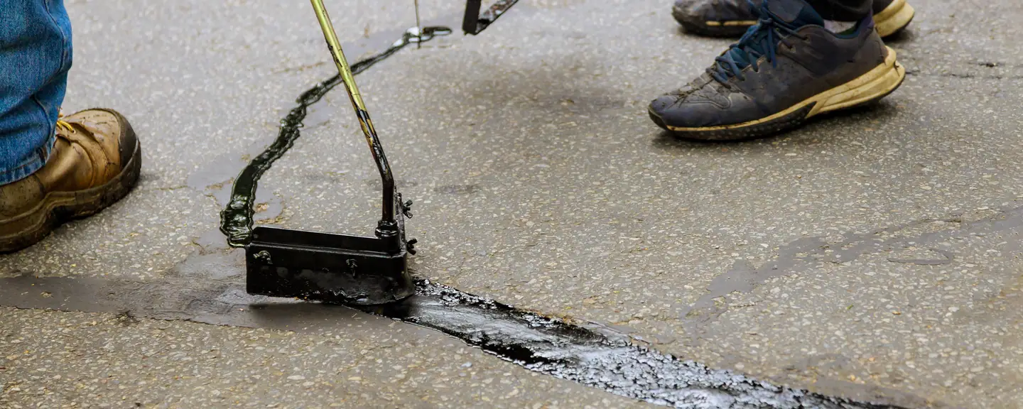 A crew treating a worn asphalt surface — Surface Dressing in Ashford by Meads Resurfacing