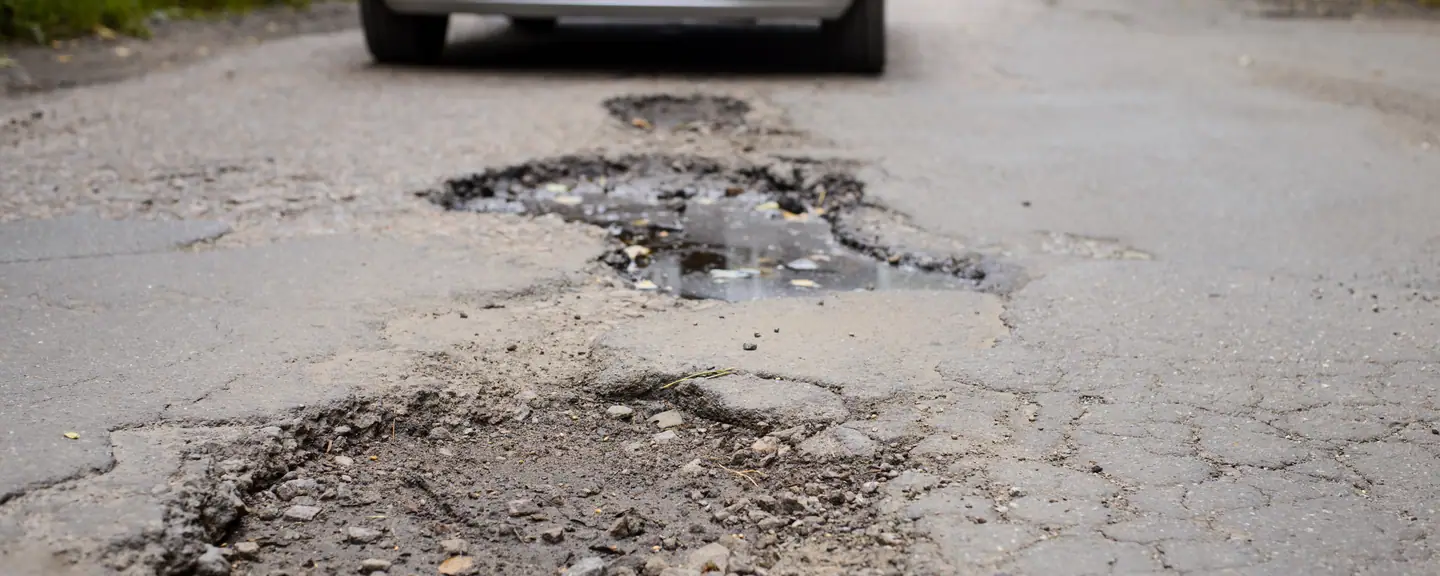 A road surface failing around an old repair — Tarmac Asphalt Repairs in Halstead by Meads Resurfacing