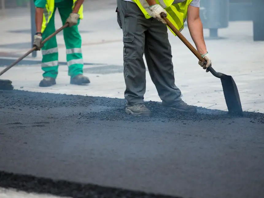 Two contractors shovelling tarmac