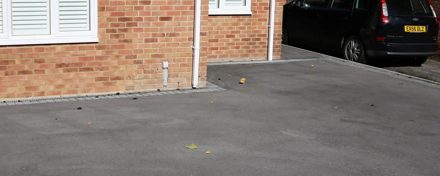 A finished tarmac driveway with a car parked on it — Tarmac Driveways in Hackney by Meads Resurfacing