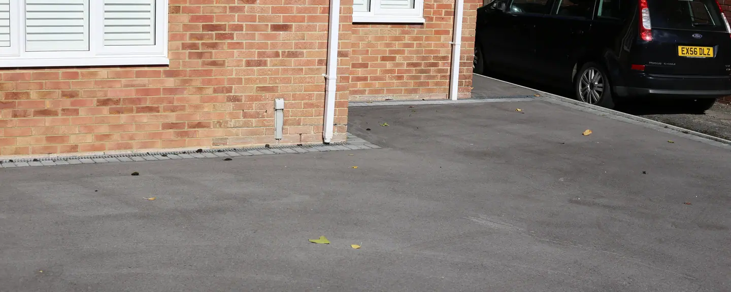 A tarmac driveway alongside a brick frontage — Tarmac Driveways in Whyteleaf by Meads Resurfacing